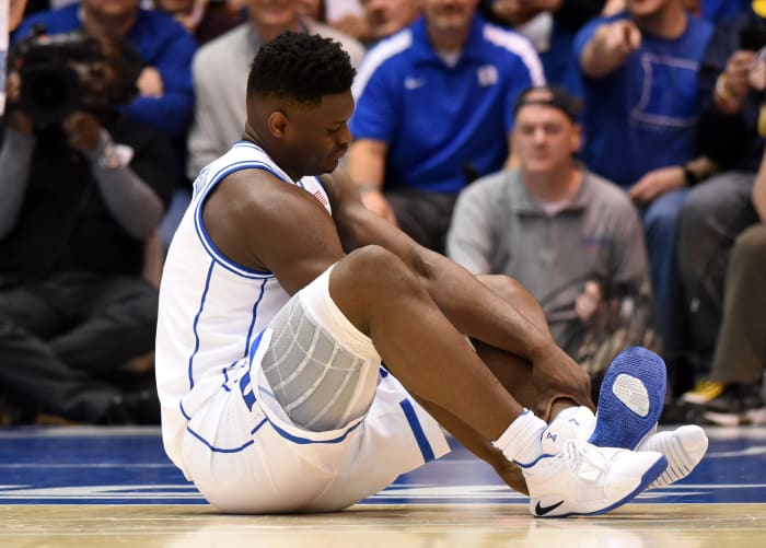Duke Blue Devils forward Zion Williamson checks on his foot after falling.